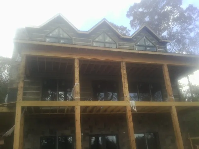 Dormers and porch framing on a large log home under construction — Roof Coating work by our crew in Limekiln
