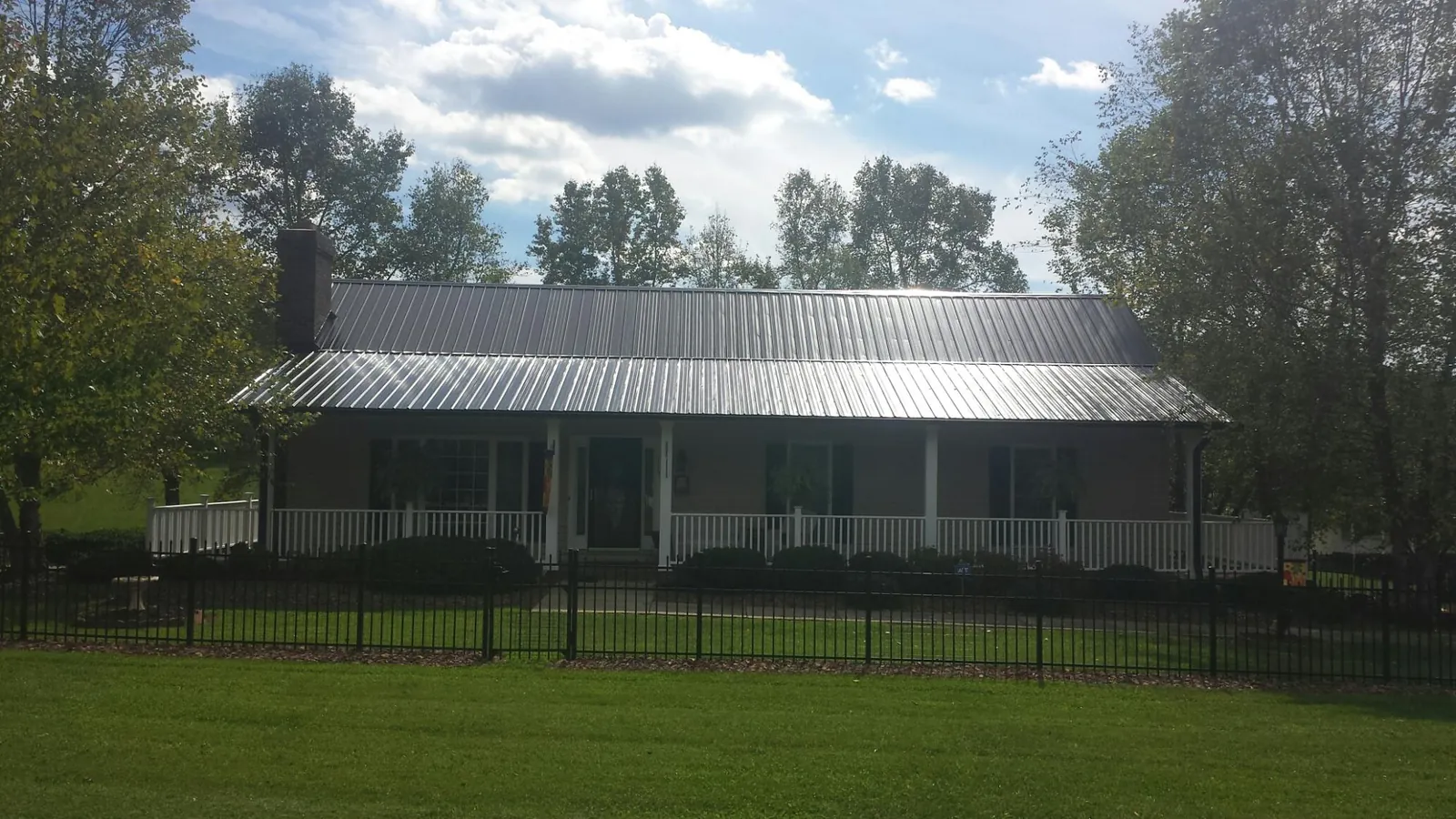 Gray metal roof on a brick ranch with a full width front porch — Gutter Guard Installation work by our crew in Limekiln