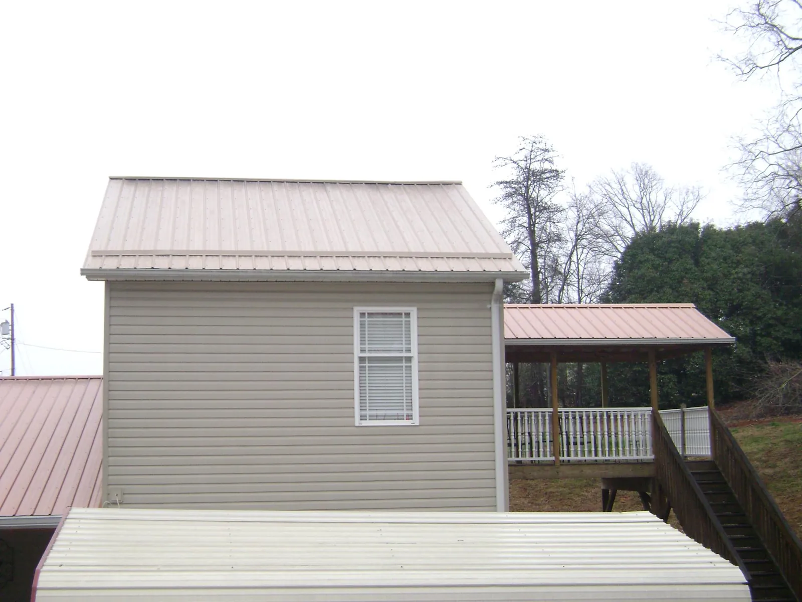 Tan metal roofs on a two story addition and attached porch, from a Roof Replacement job in Limekiln