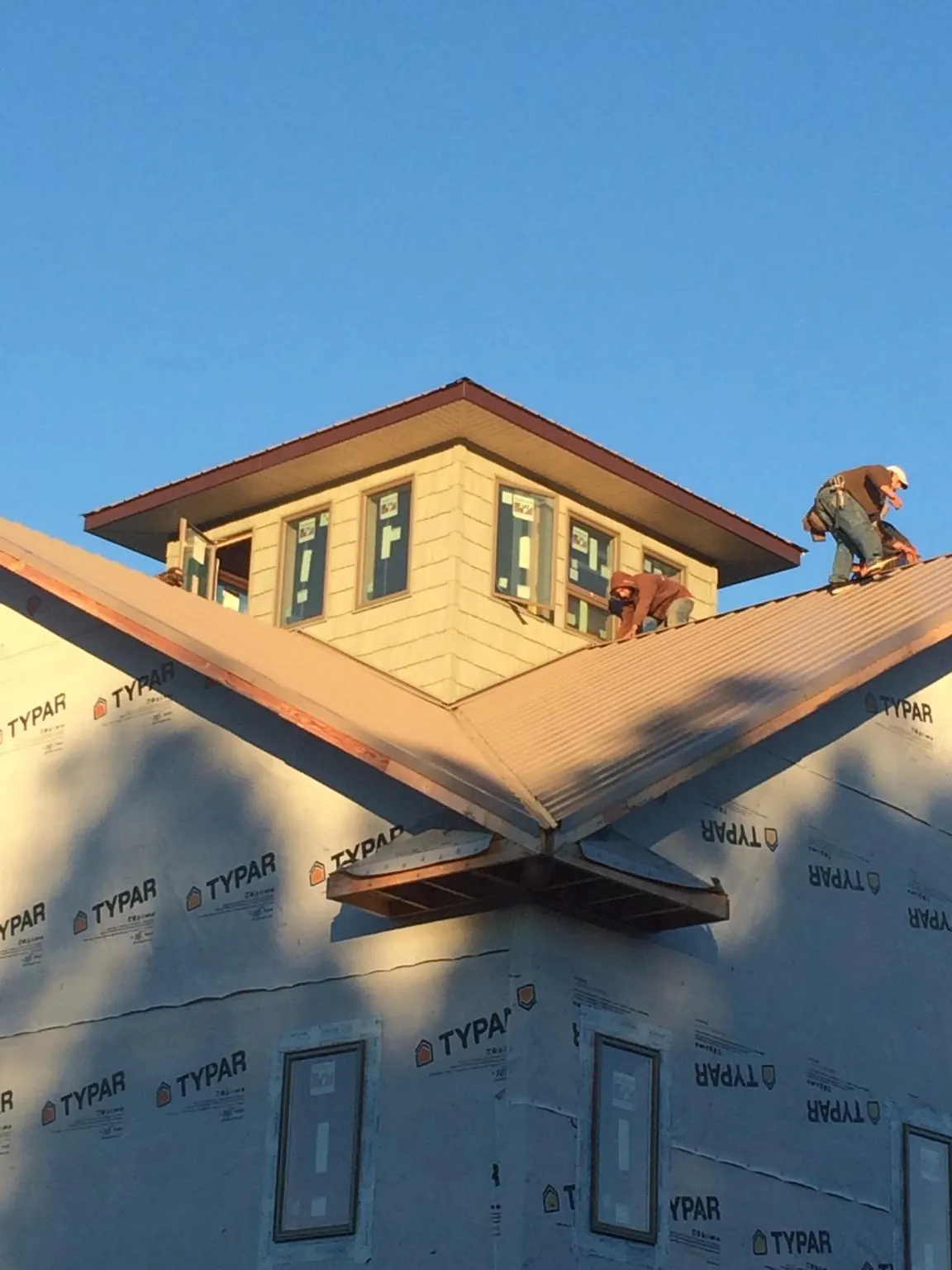 Roofers working around a rooftop cupola on a new metal roof at sunset — Roof Waterproofing in Limekiln by Roofing Brothers